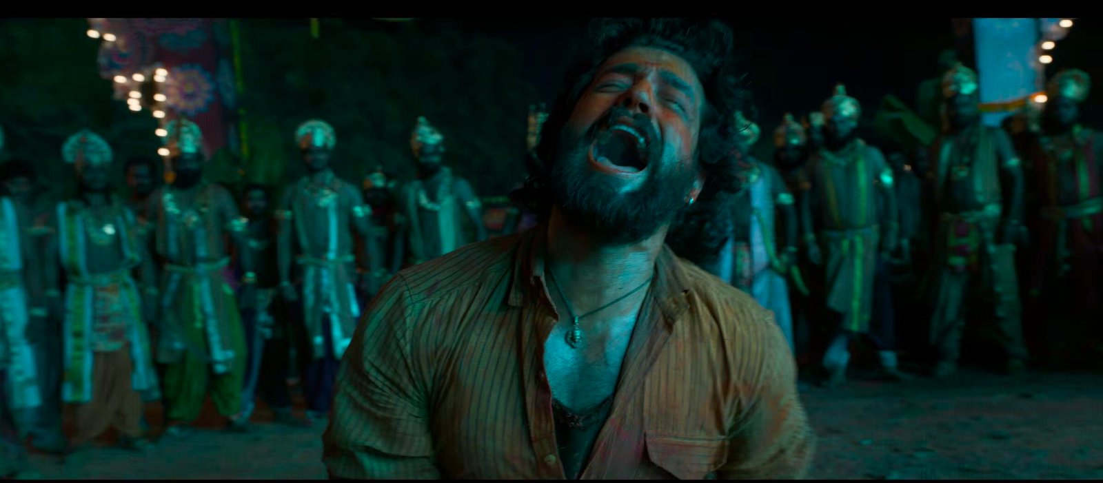 Akhil Akkineni mass transformation look in Lenin trailer scene, depicting an emotional, intense scream with warriors in a dramatic green-lit background.